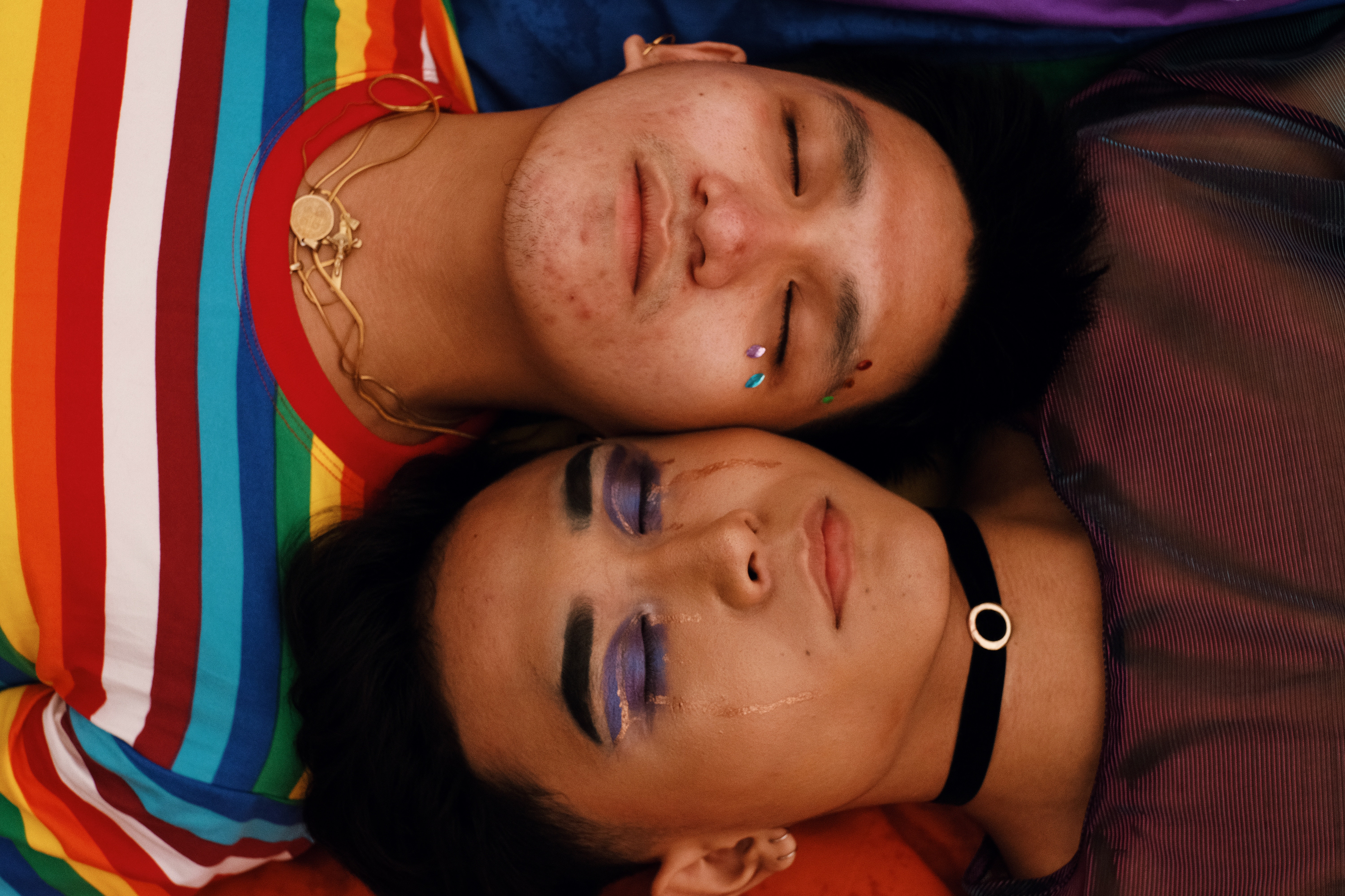 Image of two queer people lying on the ground next to each other.